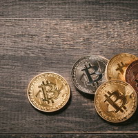 木目調の背景に置かれたビットコイン（BTC）の金色コインの写真
