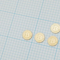 方眼紙の上に置かれた金色のビットコイン硬貨の投資の写真