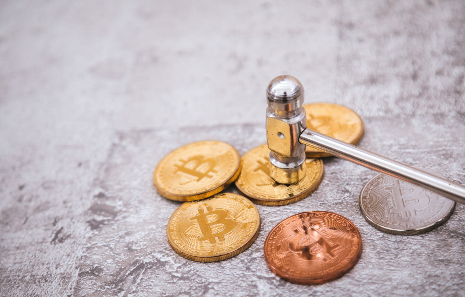 ハンマーで破壊されるビットコインコインが散らばっている