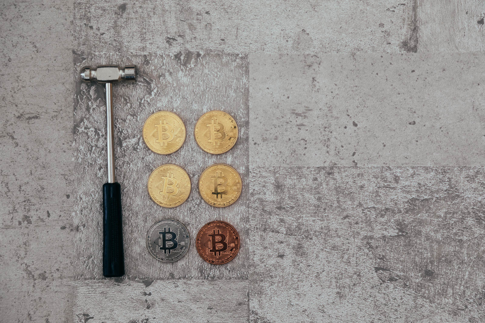 コンクリート表面に置かれた黒いハンマーと金色のビットコイン硬貨