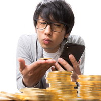 仮想通貨の価格をスマホでチェックする眼鏡の男性投資家の写真