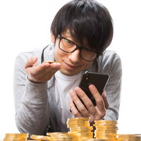 ビットコインをトレードするスマートフォン操作する男性の写真