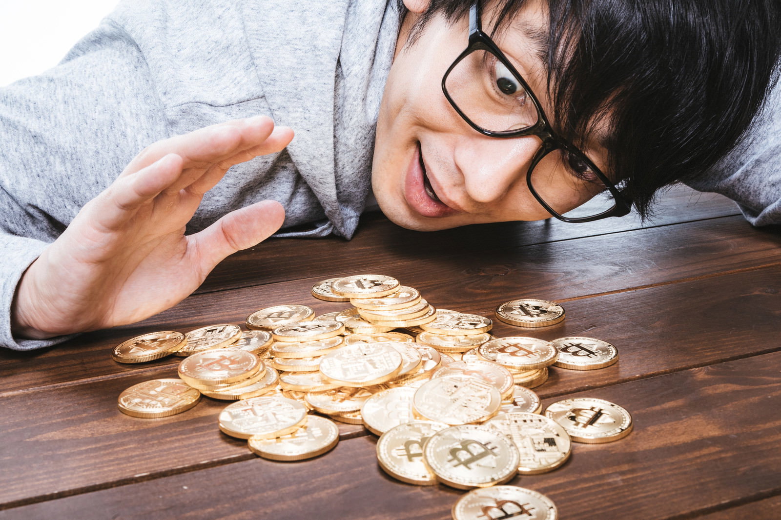 金貨を見つめる眼鏡をかけた男性［モデル：大川竜弥］