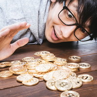 大量の金貨に驚きを隠せない億り人の男性、ビットコイン投資で大きな利益を獲得の写真