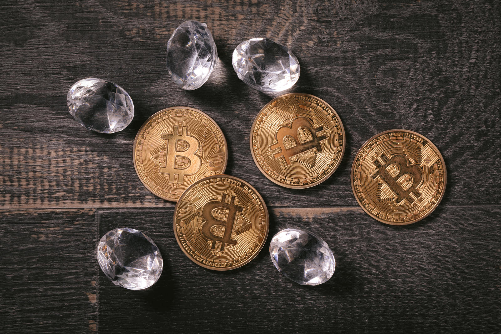 木製テーブルに置かれたビットコインコインとダイヤモンド