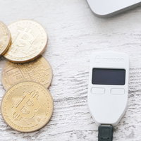 ビットコインを管理するハードウェアウォレットと金色のコインの写真