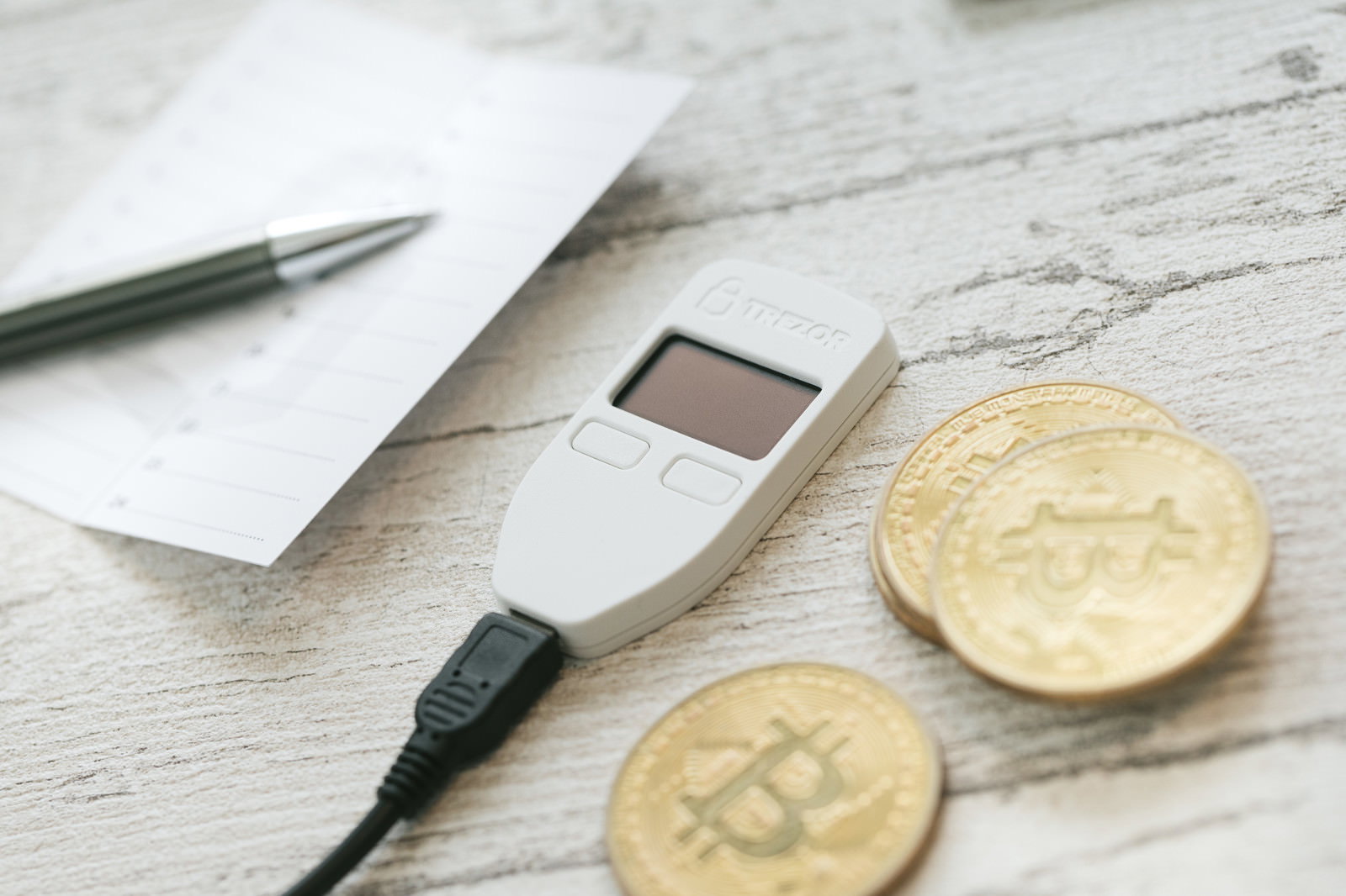木製テーブルに置かれたビットコインとハードウェアウォレット