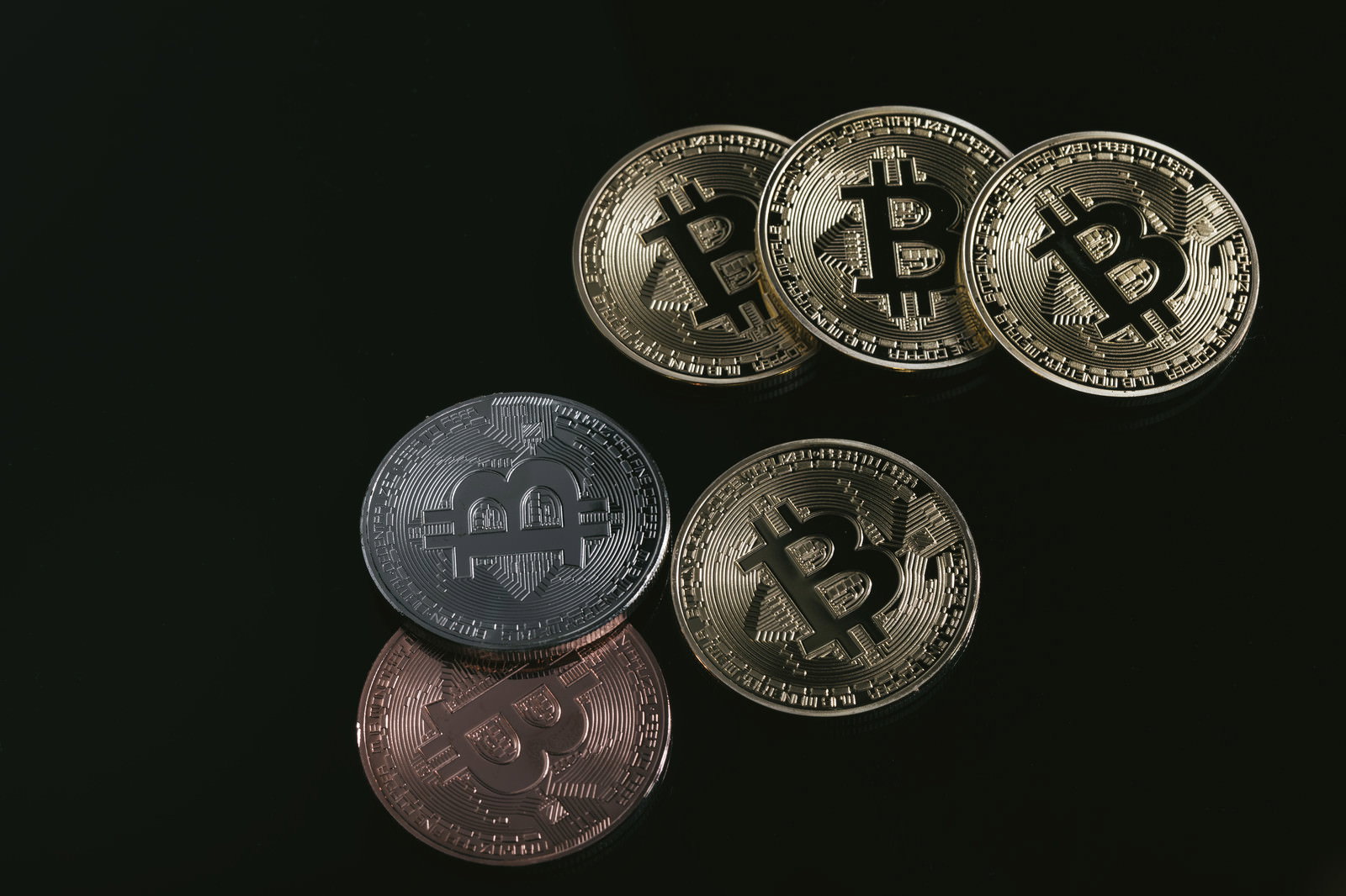 黒い背景に並んだ金銀銅のビットコインコイン