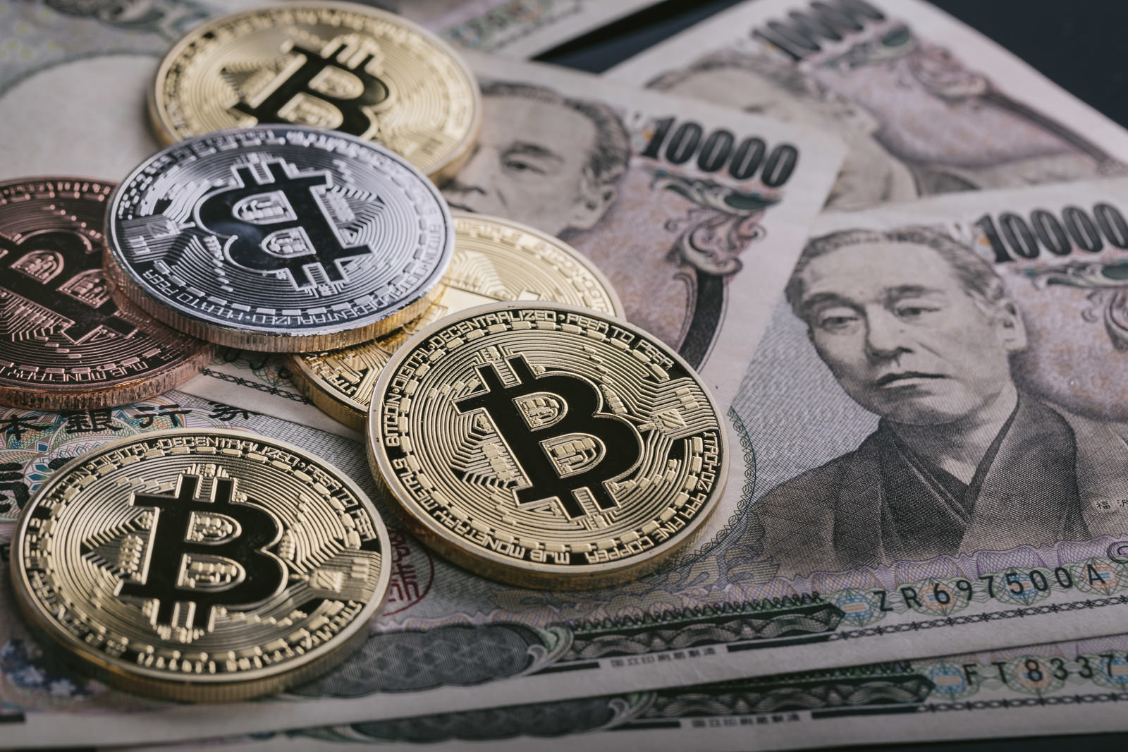 ビットコインコインが一万円札の上に置かれた写真