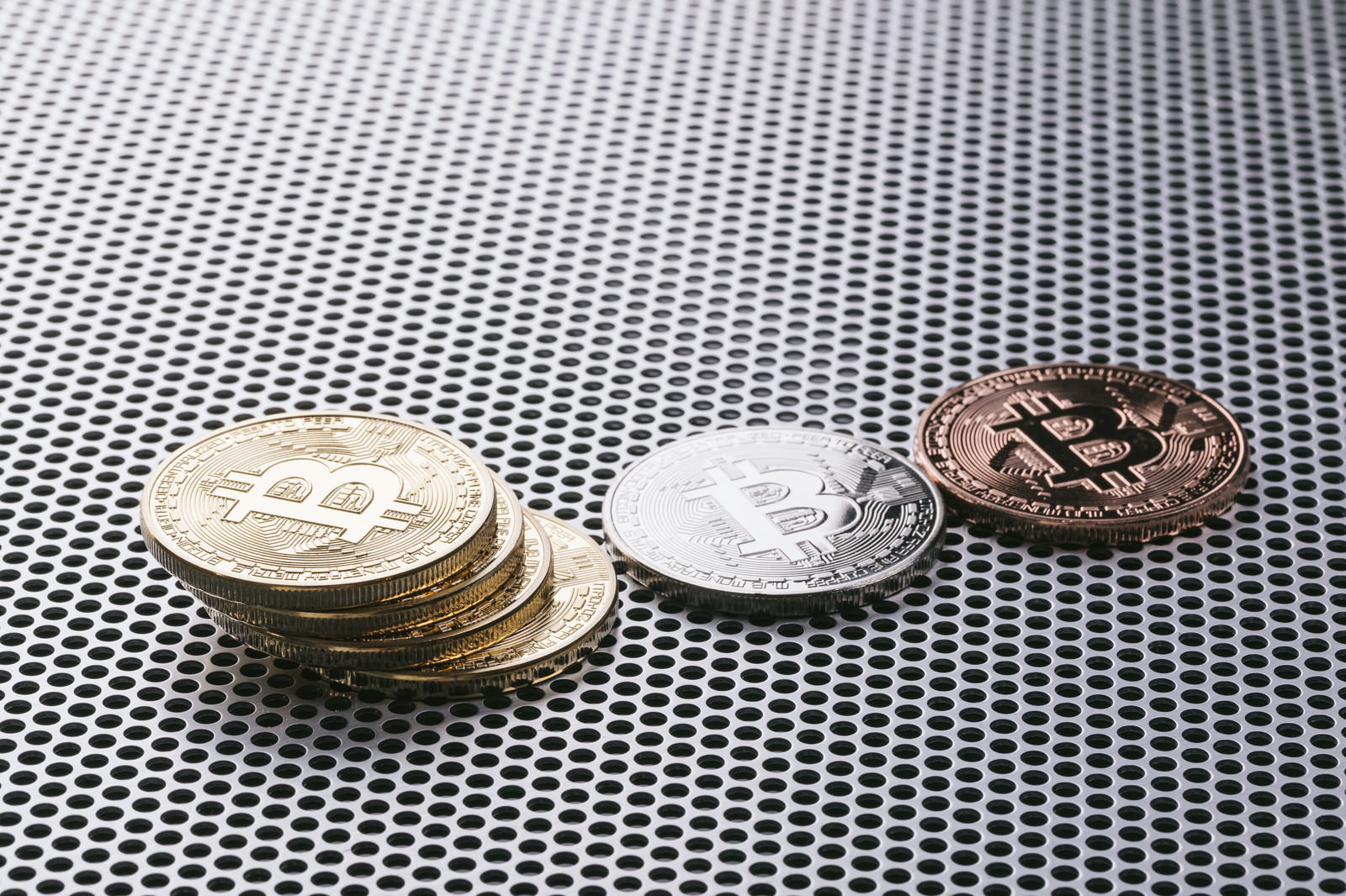 穴あきパネルの上に重なるビットコインコイン