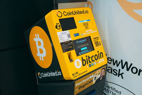 外国の黄色いビットコインATM機の操作画面と金融機器