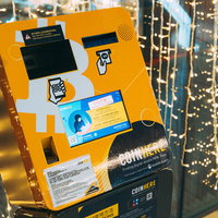 金色の電飾が光るオレンジ色のbitcoinATMの写真