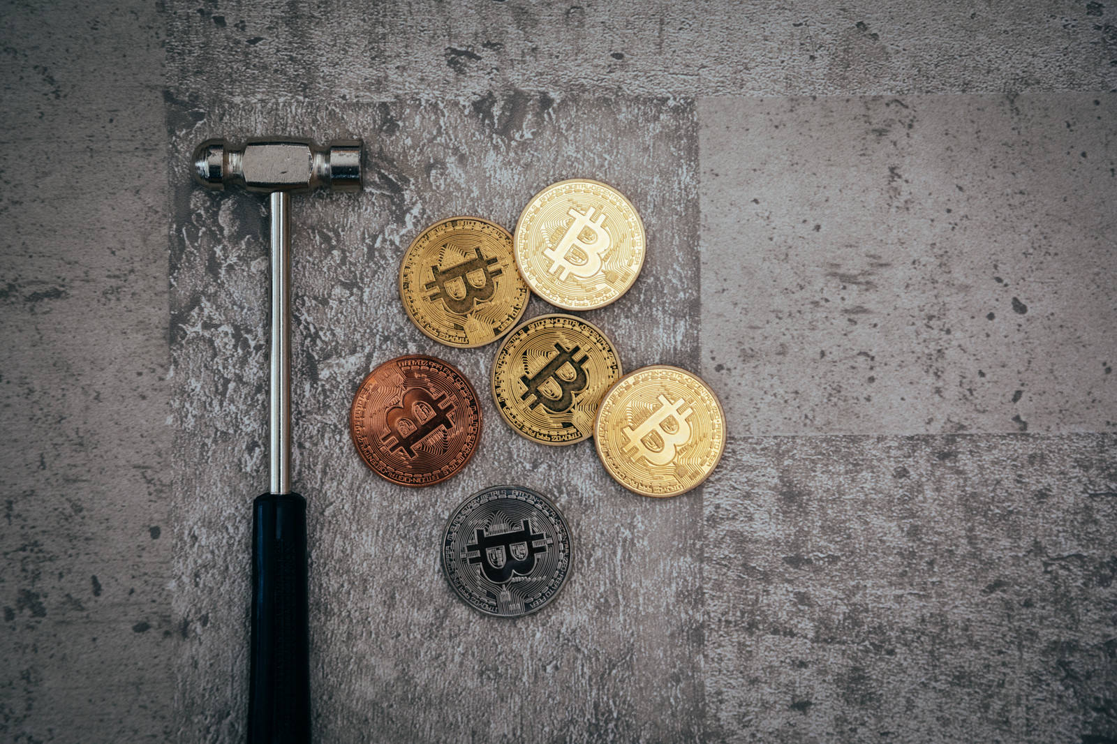 コンクリート表面に置かれたハンマーとビットコインのコイン