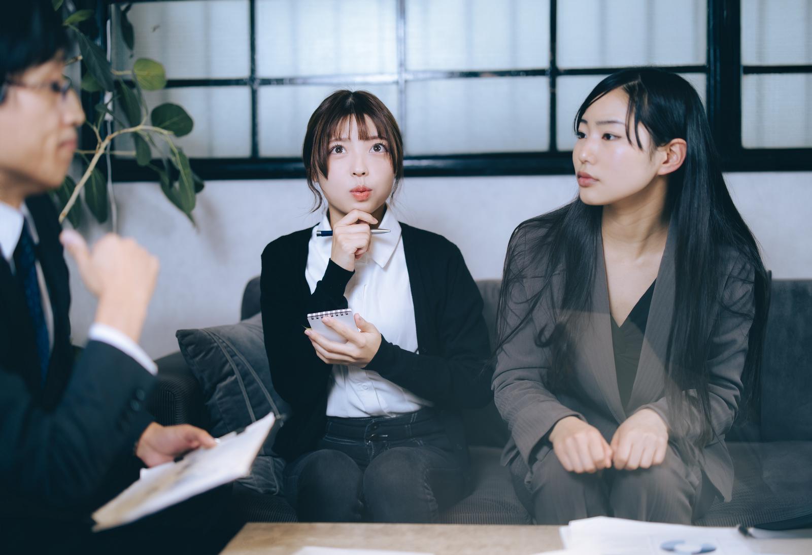 ブレストミーティングで資料を持ちながら考える女性と聞き手の男性［モデル：高尾実生 なんこ］