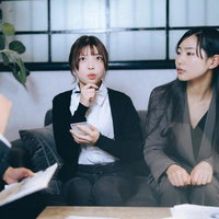 ブレストミーティングで資料を手に考える女性の写真