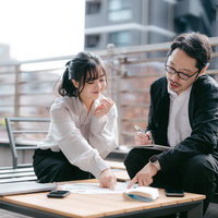 屋上テラスで資料をチェックする男女ビジネスパーソンの写真