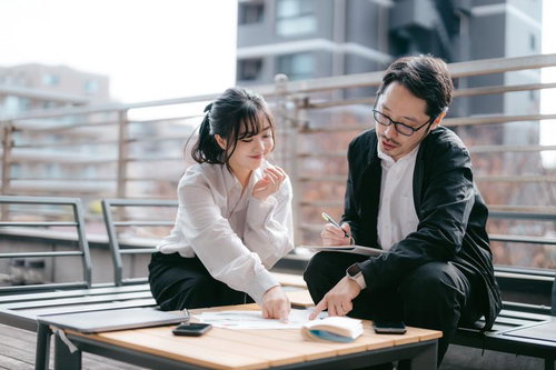 屋上テラスで資料をチェックする男女ビジネスパーソン
