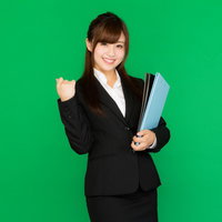 グリーンバックの書類を抱えた新卒女子社員のビジネスポーズの写真