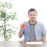 赤いハート型のヘルプマークを握るヘルプマーク所持者による認知向上の写真