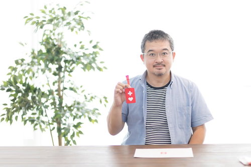 赤いハート型のヘルプマークを握るヘルプマーク所持者による認知向上