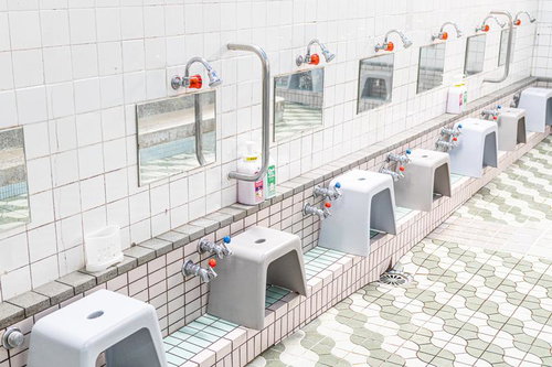 銭湯の洗い場に並ぶ蛇口と風呂椅子