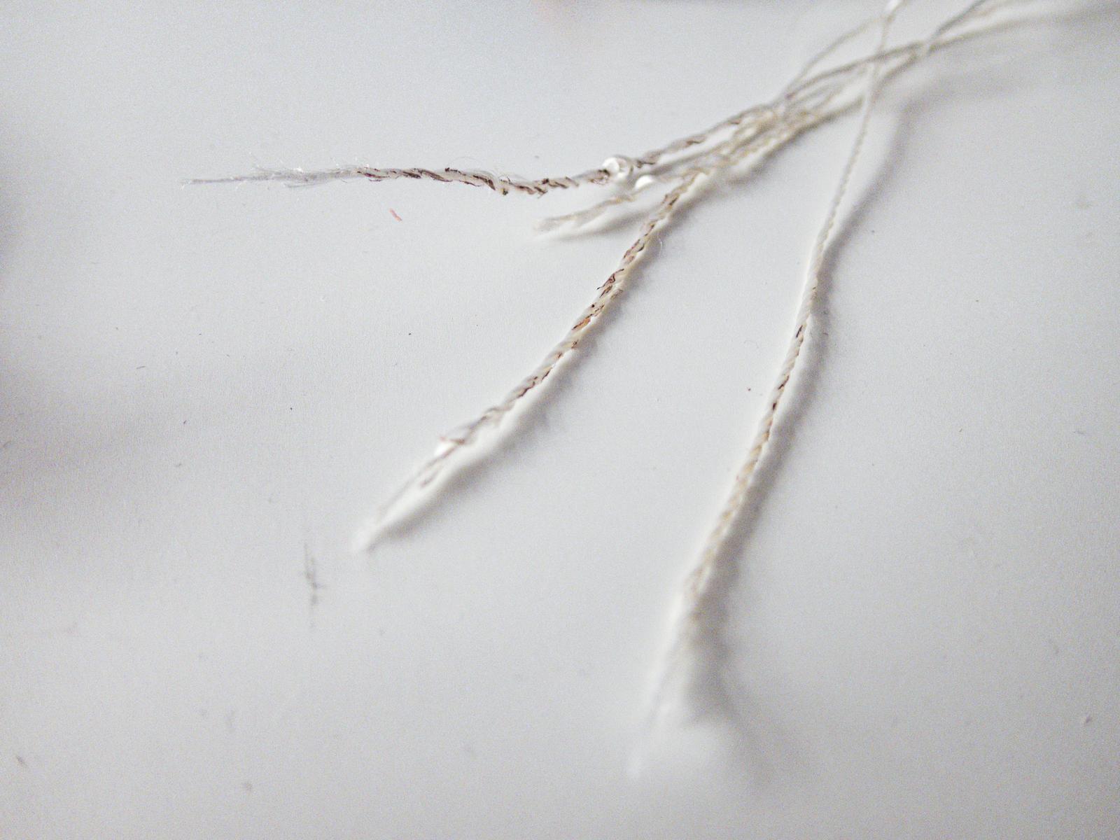白いパラコードが破断してほつれている状態を白い背景で撮影した写真