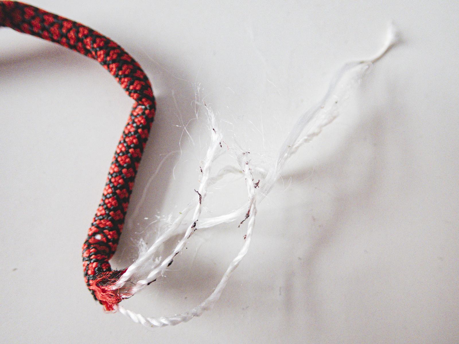 赤黒いロープが白い繊維をほぐしながら破断している様子