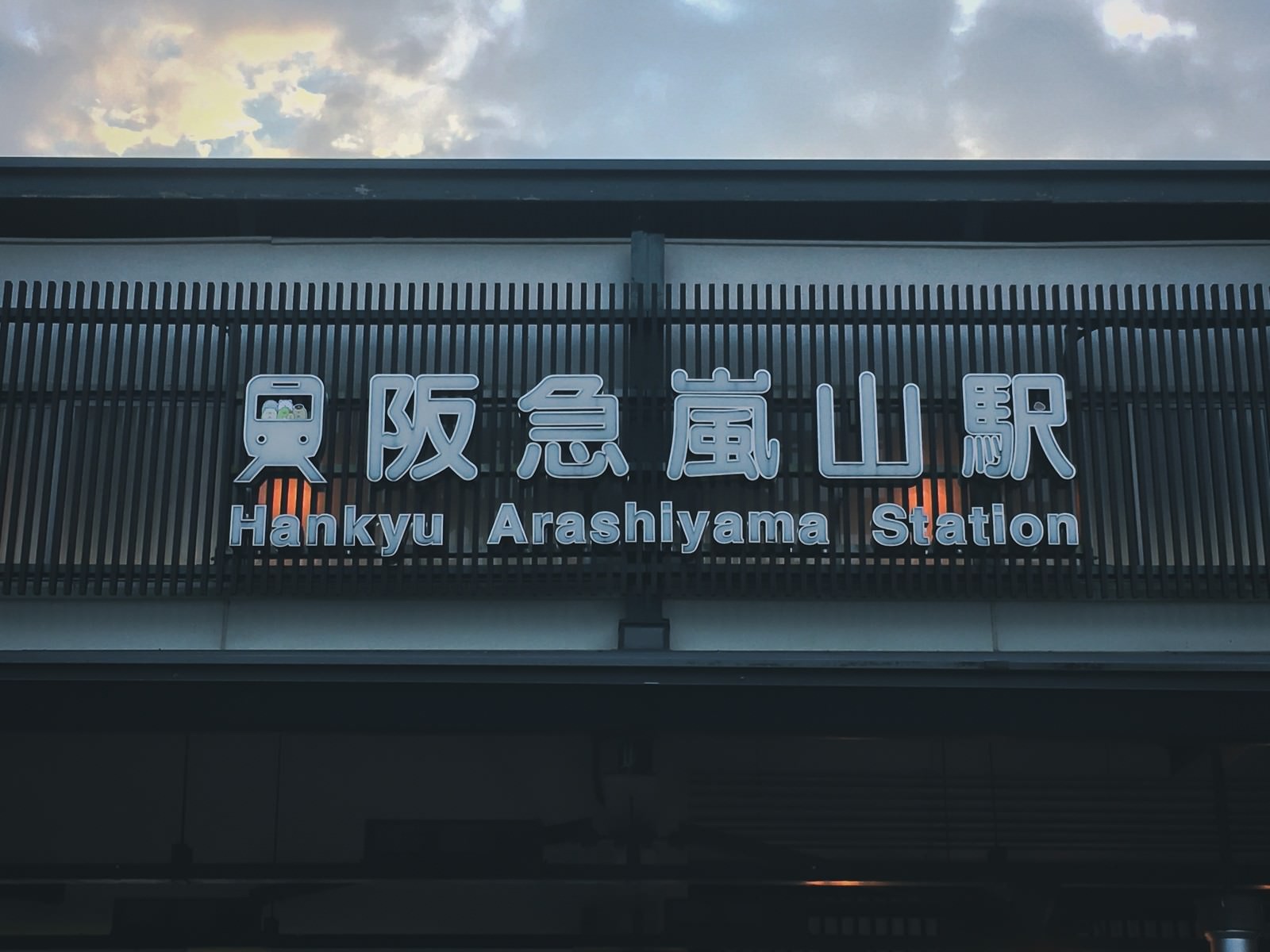 グレーの駅舎に設置された阪急嵐山駅の白い駅名看板