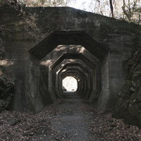 どこまでも続く八角トンネル跡、石造りアーチの廃線遺構の写真