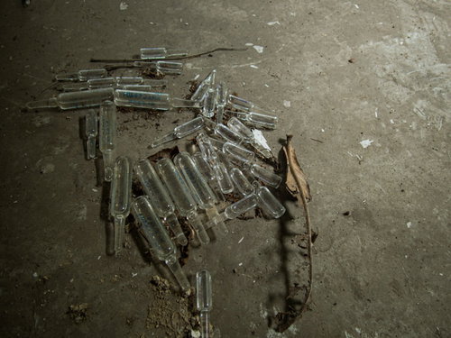 廃墟に散らばる注射液用瓶の残骸とガラス片