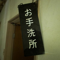 傾いたお手洗所の案内板、廃墟の古い建物の看板の写真