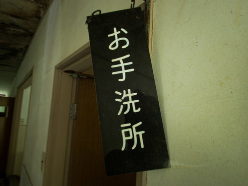 傾いたお手洗所の案内板、廃墟の古い建物の看板