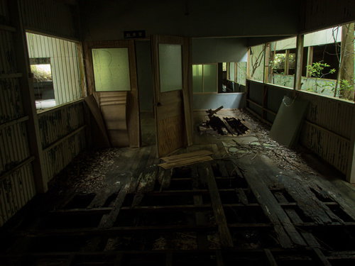 床が崩れ落ちそうな廃墟の室内、腐食した床板と損傷した壁