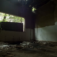 いまにも天井が崩れ落ちそうな廃部屋の床に散乱する瓦礫の写真