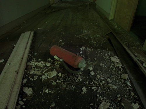 おそらく使えない廃墟に転がる赤い消化器と瓦礫