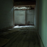 突き抜けた天井から差し込む光と散乱する崩落物の写真