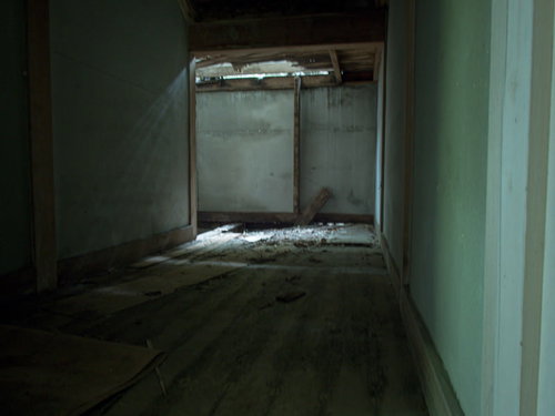 突き抜けた天井から差し込む光と散乱する崩落物