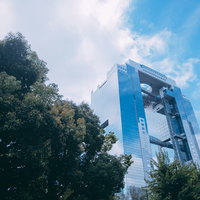 青空と緑の木々の向こうに見える梅田スカイビルの写真