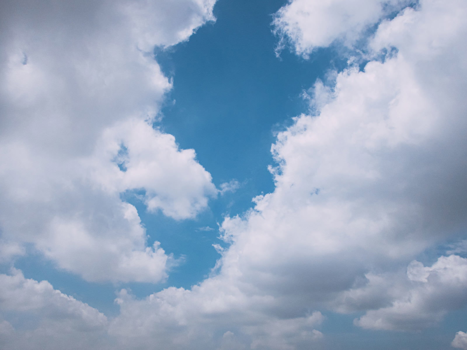 白い雲の隙間から鮮やかな青空が覗いている空の風景