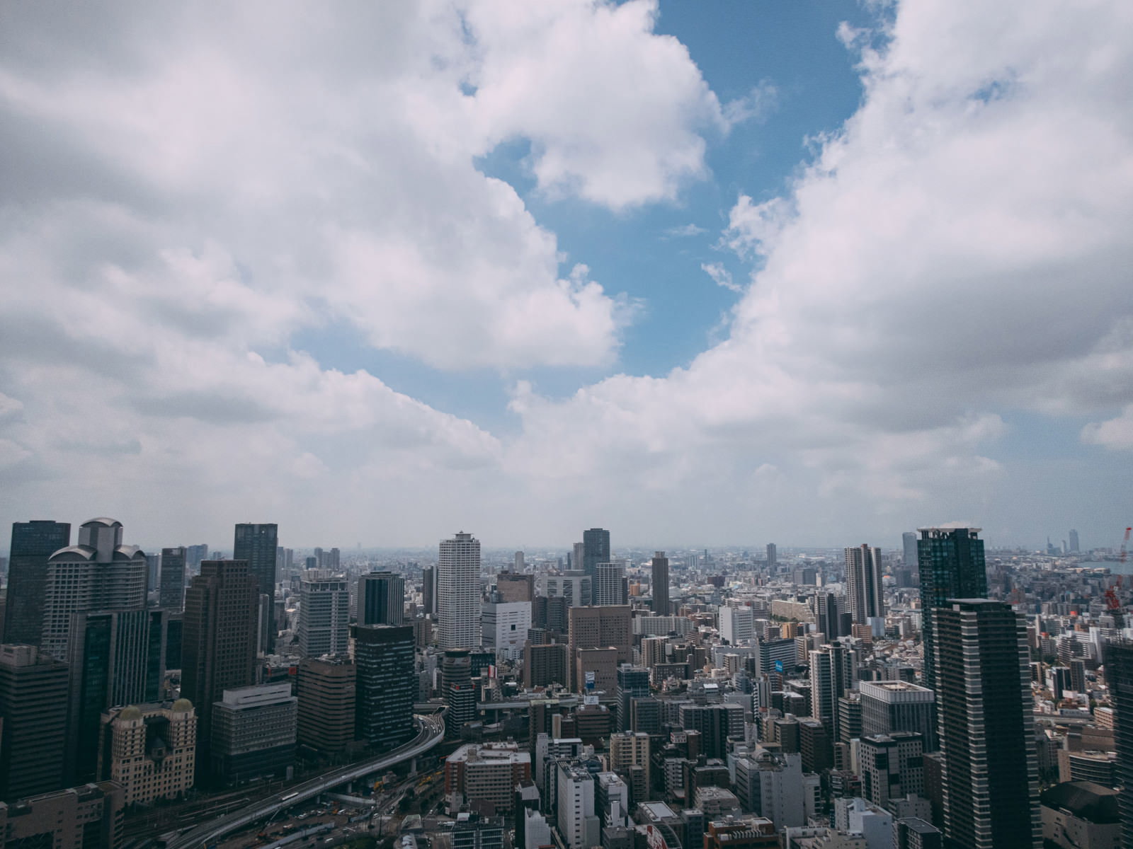 大阪梅田の高層ビル群の上空に白い雲が浮かぶ都市風景