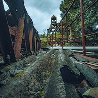 崩れ落ちたトタンと錆び付いた鉄骨が散乱する廃墟の工場の写真