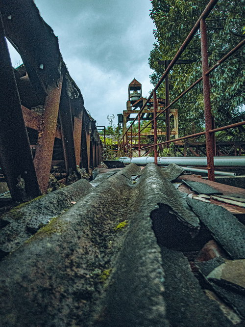 崩れ落ちたトタンと錆び付いた鉄骨が散乱する廃墟の工場