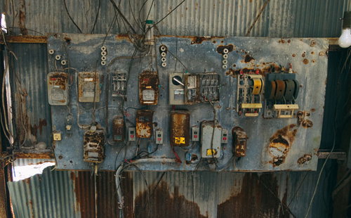 廃工場に放置された朽ちた配電盤と複数のスイッチ類