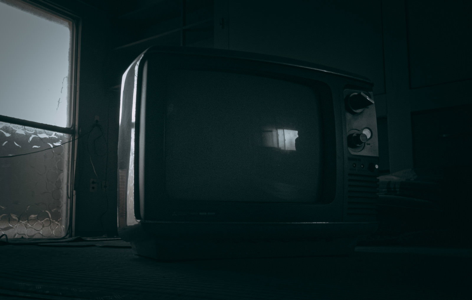薄暗い部屋に置かれた古いブラウン管白黒テレビ