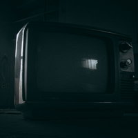 薄暗い室内に置かれたレトロなブラウン管白黒テレビの写真