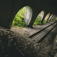 石積みアーチが一部崩落した廃線トンネルの線路跡の写真