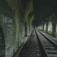 石積みアーチが連続する廃線のトンネルと線路の写真