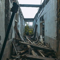 屋根も崩落して瓦礫が残る廃病院の廃墟の写真