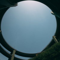 青い空の下、河津七滝ループ橋の円形橋梁と山間の道路風景の写真