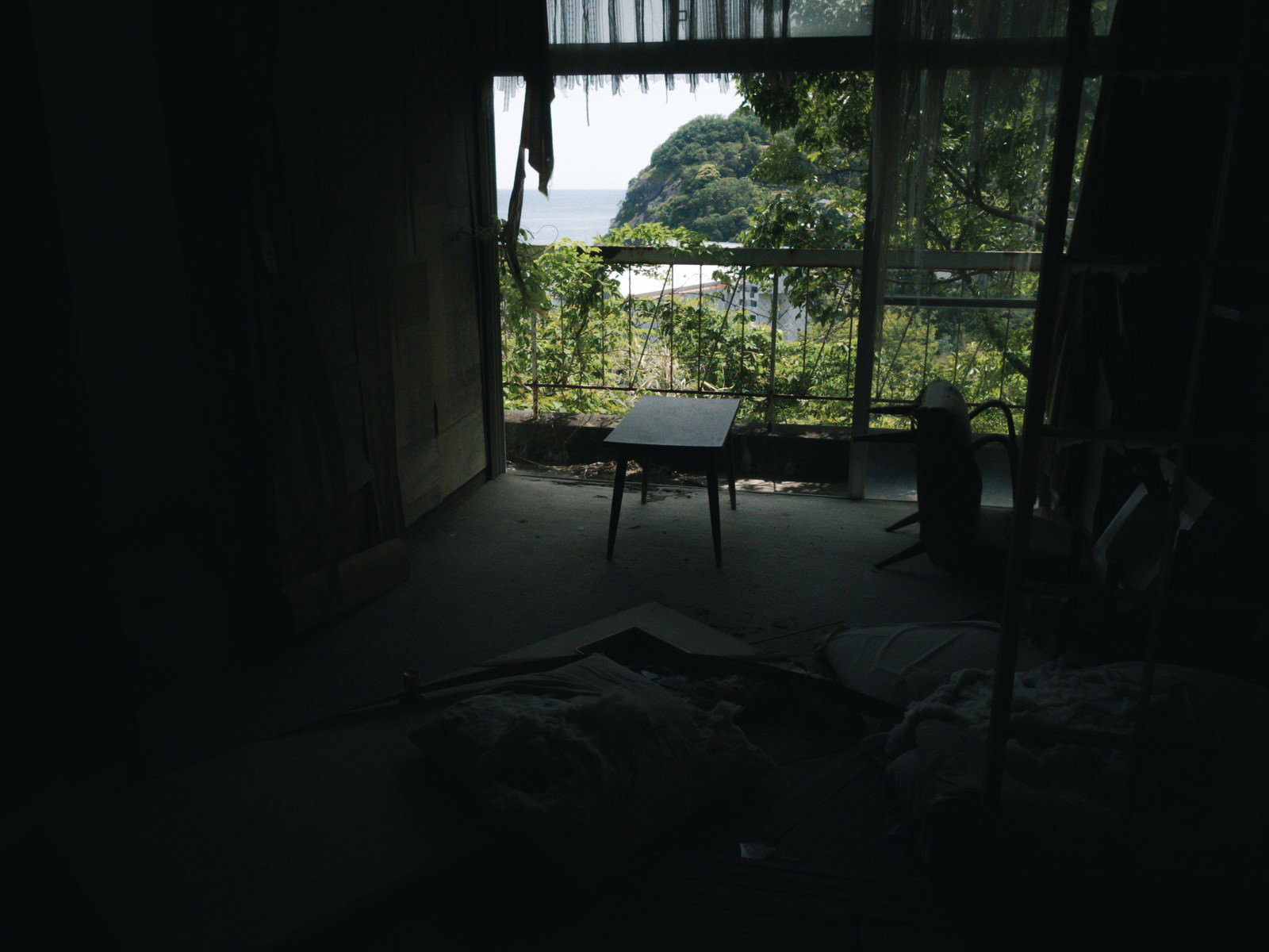 廃屋の薄暗い室内で窓辺に置かれた古びた机